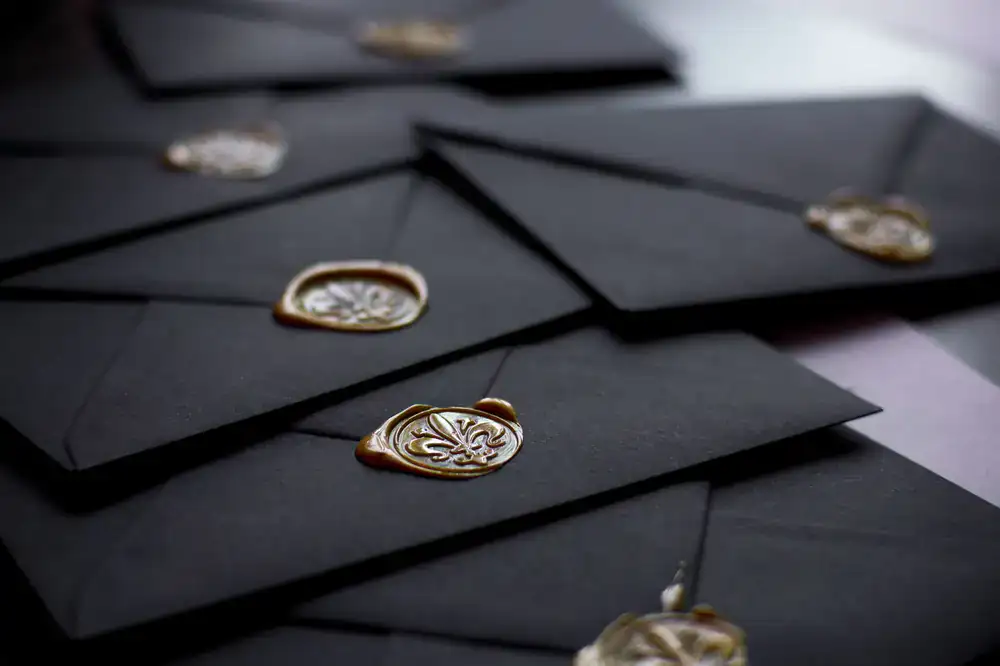 Hands opening a mysterious black envelope with a wax seal